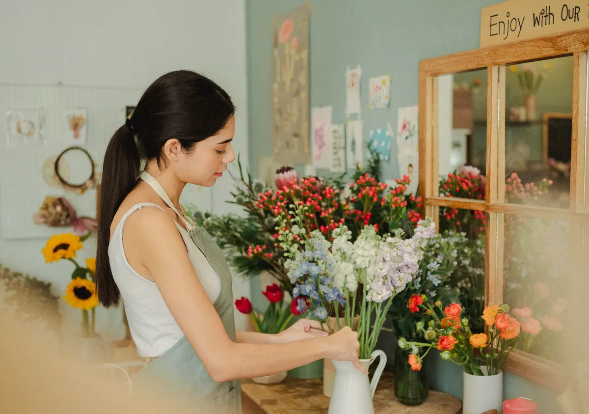 Mains de fleuriste ajustant les tiges d'un bouquet fraîchement coupé